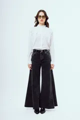 Camisa blanca de manga larga con cuello alto con volados, detalles de alforzas y pliegues en el frente y cierre frontal con botones ocultos.