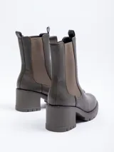 Bota tipo chelsea de caña alta confeccionada en cuero sintético, con paneles elásticos laterales, plataforma dentada y taco cuadrado.