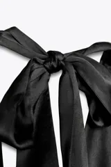 Top blanco de tejido satinado con cuello halter drapeado ajustable con lazada en el cuello y espalda descubierta con lazada.