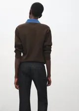 Chaleco de punto color marrón, con cuello polo y cierre frontal parcial con botones dorados, y detalles en denim en la zona del cuello.