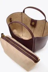 Bolso de mano tipo mini city, color borgoña, con pespuntes en contraste. Presenta asa de mano y asa bandolera extraíble. Incluye una bolsa interior extraíble con cierre de cremallera.