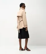 Trench coat de corte sastrero color beige, con cuello solapa, cierre frontal de doble botonadura y acabado satinado.
