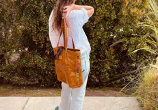 Bolso tote de cuero color marrón con costuras decorativas de hilo de colores.