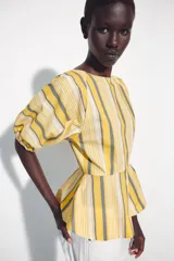 Camisa de algodón con rayas amarillas, blancas y grises, cuello redondo, mangas cortas abullonadas con puños elásticos y bajo con vuelo evasé.