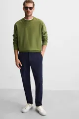 Pantalón de corte slim fit confeccionado en tejido elástico, con cintura elástica, cierre frontal con cremallera y botón, bolsillos laterales y bolsillos traseros de vivo.