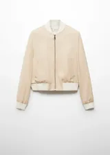 Chaqueta tipo bomber color beige, con cierre frontal de cremallera metálica, cuello, puños y ruedo en tejido de canalé blanco. Cuenta con dos bolsillos laterales de ribete.