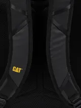 Mochila negra de estilo utilitario con compartimento principal acolchado para computador y múltiples bolsillos organizadores interiores. Presenta detalles en amarillo vibrante en las correas de compresión laterales y un parche con el logotipo de CAT en la parte inferior frontal.