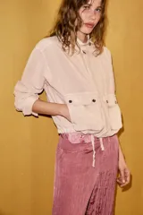 Chaqueta Zara de corte holgado con efecto lavado, cuello subido, cierre frontal con cremallera y botones a presión. Presenta dos bolsillos de plastrón con solapa y botones en el delantero, mangas largas y bajo ajustable con cordones.