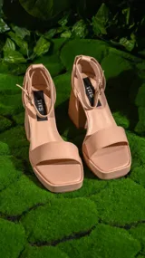 Sandalias negras de cuero sintético, con plataforma y taco cuadrado. Tiras anchas sobre el empeine y pulsera al tobillo con hebilla metálica.