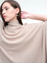 Poncho amplio de cuello alto, confeccionado en hilado con lana y cashmere, con diseño de caída recta y botones laterales.