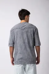 Remera de corte oversize con efecto de lavado gastado, confeccionada en algodón pesado. Presenta cuello redondo, mangas cortas con costuras visibles y un diseño amplio.