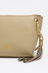 Bolso bandolera de estructura rígida y tamaño mediano confeccionado en piel vacuna. Presenta asa regulable, cierre con cremallera, bolsillo interior y logo metálico de la marca. Incluye un charm decorativo con borlas en el lateral y acabados metálicos.