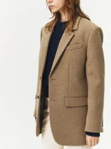 Blazer color marrón claro confeccionado en lana, de corte recto, con solapas de muesca, cierre con dos botones y bolsillos con solapa.