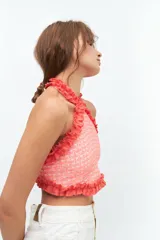 Top de escote halter confeccionado en broderie de algodón y bordado con hilo color coral. Enmarcado con voladitos de lino a tono.