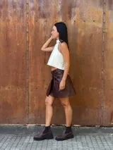 Minifalda tipo pareo confeccionada en cuero color chocolate, con diseño cruzado y cierre mediante tiritas laterales ajustables.