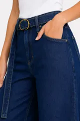 Pantalón jean de tiro alto y corte ancho, color celeste claro, con bolsillos laterales y cinto de la misma tela con hebilla metálica circular doble.
