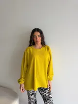 Buzo de punto acanalado color amarillo mostaza, de corte holgado, cuello redondo y mangas largas con puños fruncidos.