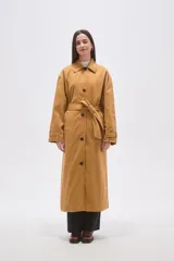 Trinchera larga de corte holgado, con cuello solapa, cierre frontal con botones y cinturón ajustable a la cintura. Cuenta con mangas largas y bolsillos laterales.