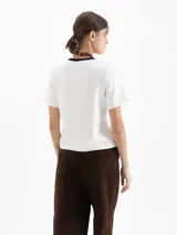 Remera de jersey pesado color blanco, con cuello redondo en contraste negro y estampa central de un corazón con diseño animal print atravesado por una flecha.