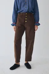 Pantalon de corte barrel en pana color marrón, con cierre frontal de botones metálicos dorados y costuras reforzadas en las rodillas.