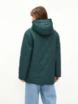 Campera acolchada de color verde oscuro con diseño matelasseado, interior forrado en corderito sintético color beige, con capucha y cierre frontal de botones a presión.