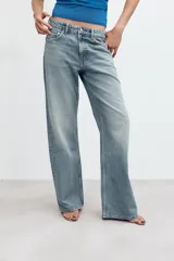 Jeans de denim de tiro medio y corte relaxed con diseño de cinco bolsillos, trabillas en la cintura y cierre frontal con cremallera y botón metálico.