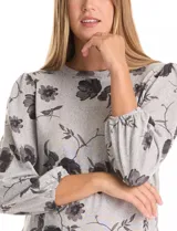 Buzo de tejido soft estampado, con cuello a la base y mangas largas con terminación fruncida. Presenta un diseño floral en tonos oscuros sobre base gris.