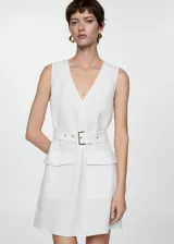 Vestido corto de color blanco con cuello en pico y diseño sin mangas. Presenta un corte recto, tirantes anchos y dos bolsillos de solapa en la parte delantera. Incluye un cinturón ajustable con hebilla metálica en la cintura.
