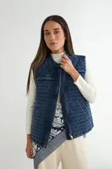 Chaleco de denim acolchado con cierre frontal, diseño de cuello redondo y bolsillos laterales. Presenta un patrón de costuras horizontales en el cuerpo y rombos en la parte superior.