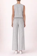 Conjunto de dos piezas en tejido de punto jaspeado color gris. Incluye un chaleco con escote en V y cierre frontal de botones, y un pantalón de corte recto con cintura elástica.