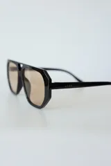 Lentes de sol con armazón de policarbonato negro y cristales tonalidad ámbar, con diseño de puente doble estilo aviador.
