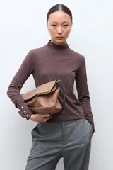 Media polera de manga larga en color chocolate melange, con cuello alto y detalle de frunces en los puños con botones decorativos.