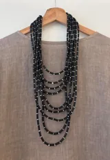 Collar de nueve capas a distintas alturas con canutillos negros y cuentas blancas.