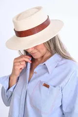 Sombrero de algodón tejido estilo fedora, color mostaza, con cinta de cuero marrón decorativa alrededor de la copa.