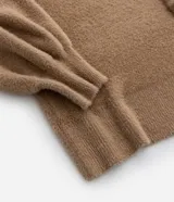 Suéter color beige de punto con textura de pelitos, cuello alto y mangas largas.