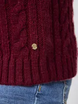 Sweater de tejido grueso con textura trenzada, cuello alto y mangas largas.