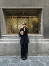 Blazer negro de lana con rayas verticales finas, corte clásico, solapas de muesca y cierre con botones.