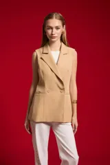 Chaleco sastrero de poliéster color beige, con solapa ancha, doble botonadura frontal y bolsillos de ribete simulados.