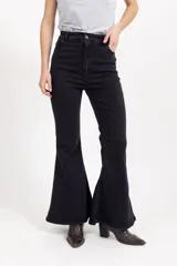 Jean oxford de tiro alto en color negro, confeccionado en denim con elasticidad. Presenta un corte ajustado en la parte superior y acampanado desde la rodilla hacia abajo, con cierre frontal y bolsillos.
