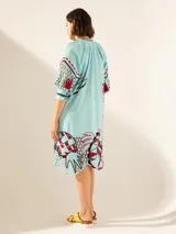 Túnica celeste con estampado de motivos botánicos en rojo y negro.