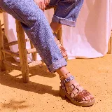 Sandalias de plataforma baja con múltiples tiras frontales y tobillera ajustable con hebilla, combinando tonos marrón, beige y texturas estampadas.