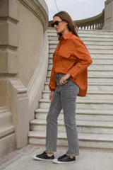 Camisa beige oversize de manga larga con cuello clásico, cierre frontal con botones y dos bolsillos con solapa en el pecho.