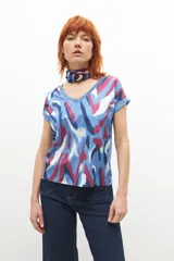 Blusa celeste con estampado abstracto en tonos azules, rosados y blancos, con escote en V y mangas cortas con dobladillo.
