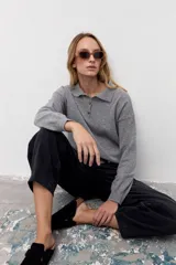 Sweater de punto color gris, con cuello polo y cierre frontal parcial de botones, de manga larga y diseño holgado.