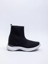 Zapatilla negra de textil elastizado, de caña media y calce tipo media. Detalle de pieza de PU en el talón.