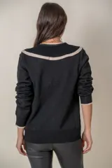 Cárdigan negro de punto fino con hilos de lurex, cuello en V calado con volados color crema, cierre frontal con botones con strass y puños anchos con ribete color crema.