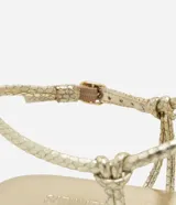 Sandalia plana dorada con punta de hoja y tiras finas con textura de serpiente. Ajuste con hebilla en el tobillo.