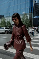 Chaqueta efecto piel color marrón, con cuello solapa, mangas por debajo del codo, cintura elástica, falsos bolsillos delanteros y cierre frontal con cremallera.