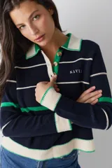 Buzo de punto estilo polo, con diseño a rayas horizontales en azul marino, verde y crema. Presenta cuello camisero con cierre frontal de tres botones, mangas largas y puños acanalados. Incluye el logo de la marca bordado en el pecho.