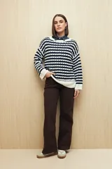 Sweater de punto con diseño de rayas horizontales en azul marino y blanco, con detalle de calados y cuello redondo. Presenta mangas largas con puños acanalados y un corte relajado.